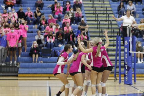 The team huddles together, cheering, after winning a long rally. 