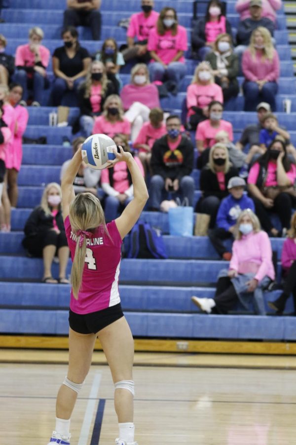 Liv McDannel (senior) sets the ball as the sea of pink fans looks on.