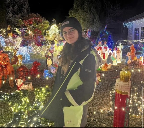Elasgaray stands in front of light displays during the Christmas season.